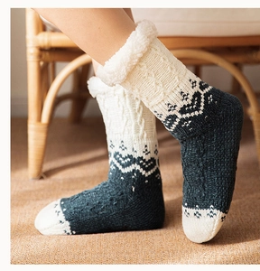 Close-up of cable knit winter floor socks with navy Nordic pattern and fuzzy white cuffs