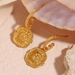 Macro shot of 18K gold plated steel earrings with sunburst coin and twisted texture
