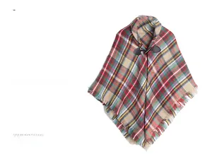 Detail of red plaid poncho cape featuring a leather toggle button and fringe edges