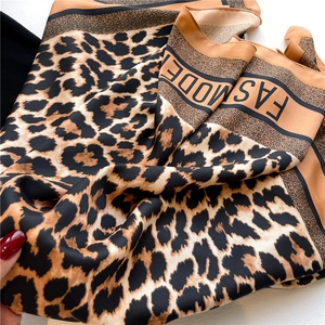 Detailed view of leopard print silk scarf with FASHMODE text and orange rolled edges