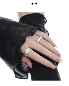 Detail of silver rose flower ring and multi-layer band set worn on model's hand