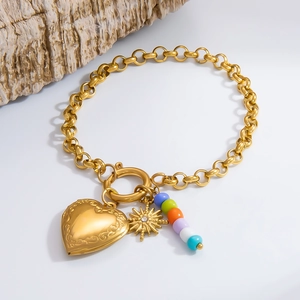 Detail of gold heart locket charm and colorful bead cluster on chunky chain bracelet