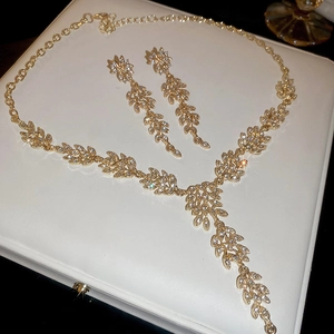 Détail macro d'une parure de bijoux feuilles avec cristaux sur boîte en cuir blanc