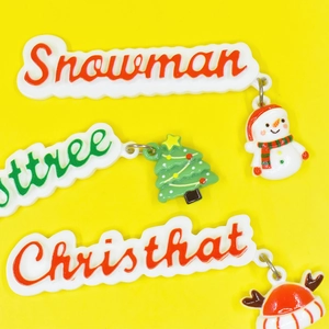 Detail of DIY Christmas resin charms featuring snowman, tree and hat on yellow background