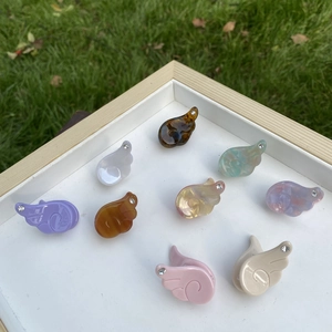 Barrettes ailes en résine multicolore avec strass disposées dans un plateau blanc
