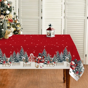 Festive red Christmas tablecloth featuring snowmen and trees on a cozy wooden dining table