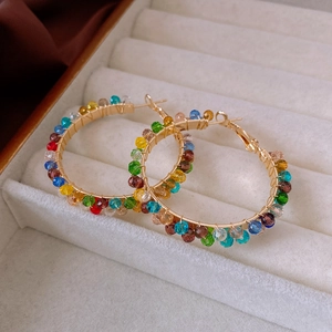 Detail of colorful faceted crystal beads wrapped around gold hoop earrings