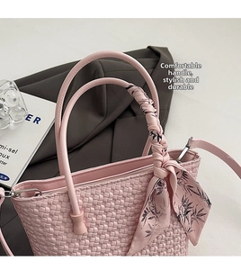 Detail of pink woven bucket bag featuring elegant silk scarf handle and leather strap