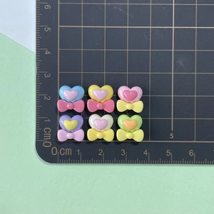 Detailed view of mini resin heart bow charms with 1.5cm measurement on a cutting mat