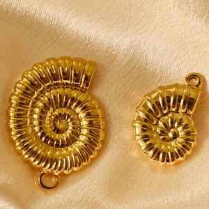 Golden seashell charms made of stainless steel on a luxury silk fabric background