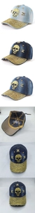 Close-up of washed denim baseball cap featuring gold skull ornaments and metal rivets