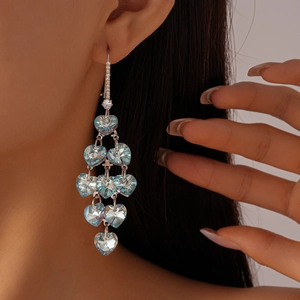 Détails de boucles d'oreilles vintage cœur à pompons avec cristaux bleus sur un modèle femme