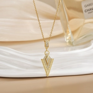 Detailed view of a gold arrow pendant necklace with cubic zirconia and Greek key pattern