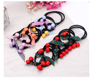 Detailed view of cherry hair ties with colorful bows and elastic bands on a wooden desk