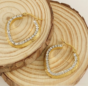 Close-up of gold U-shaped hoop earrings with zircons and Greek key pattern