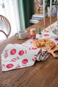 Detail of Christmas table runner featuring red candy and ball prints on linen fabric