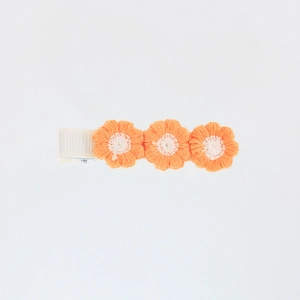 Close-up of three orange embroidered yarn flowers on a ribbon-wrapped hair clip