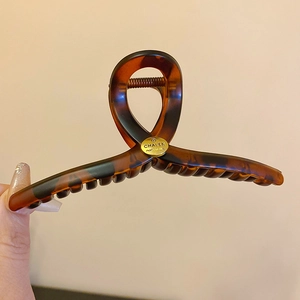 Close-up of a tortoiseshell hair claw clip with dark brown amber patterns and gold spring