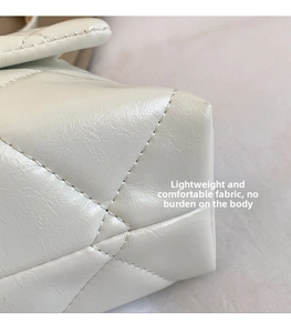 Close-up of cream-white quilted leather texture and fine stitching on a square bag