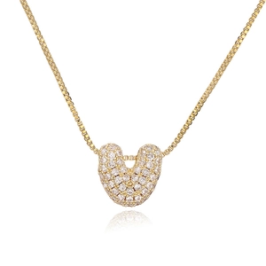 Detail of gold box chain necklace with a bubble letter U pendant set in sparkling zircon