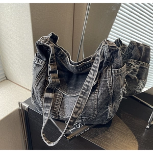 Gros plan d'un sac cabas en denim délavé avec franges usées et boucle en métal
