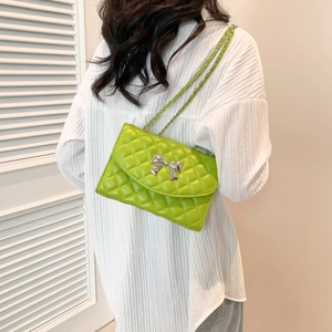 Sac à bandoulière matelassé vert avec nœud argenté et chaîne porté par un mannequin