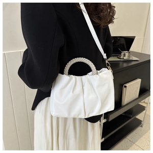 Detailed view of white pleated cloud bag with elegant pearl handle and PU leather texture