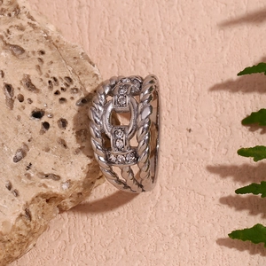 Macro detail of silver twisted band ring with H-shaped crystal link on stone surface