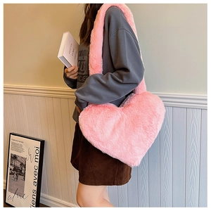 Pink heart-shaped faux fur shoulder bag shown being worn by a model in a stylish setting