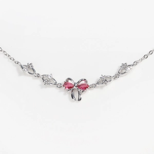 Detailed macro view of silver bow pendant with pink gemstone and zircon settings