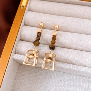 Detail of unique golden chair pendant earrings with tiger eye beads in a jewelry box