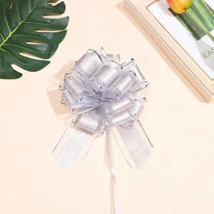 Silver pull bow ribbon for gift wrapping with metallic grid texture on pink backdrop