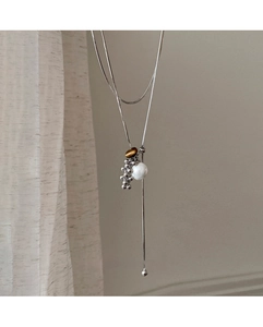 Detail of silver snake chain necklace with tiger eye stone and white pearl pendant