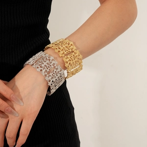 Macro shot of wide hollow lace pattern cuffs in vintage gold and silver finishes