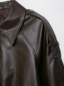 Detail of dark brown faux leather bomber jacket showing shoulder straps and stitching