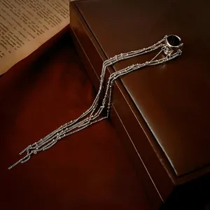 Irregular C-shaped silver tassel ear cuff displayed on vintage leather gift box