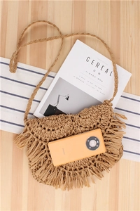 Detailed close-up of handmade woven crochet bag with tassels and shoulder strap on table