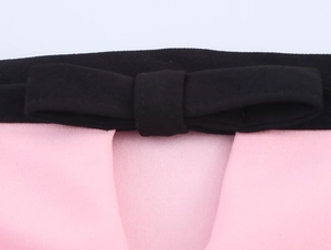 Dettaglio macro del fiocco nero decorativo e del tessuto strutturato sul top con spacco