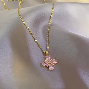 Close-up of pink clover necklace with gold chain on elegant purple silk background