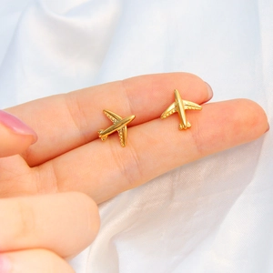 Minimalist 18K gold plated airplane stud earrings shown on hand with a soft background