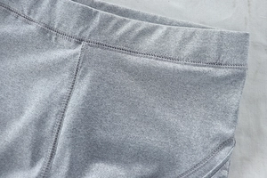 Detailed close-up of high-waist elastic waistband and stitching on grey yoga pants