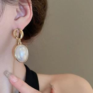 French vintage oval faux pearl gold hoop earrings for women on model closeup