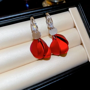Macro shot of red petal tassel earrings with sparkling zircon stones in a velvet jewelry box
