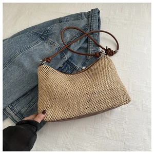 Detail of woven straw shoulder bag with zipper closure and brown leather straps
