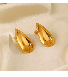 Detailed view of gold teardrop earrings with a mirror-polished finish on silk fabric
