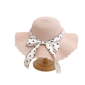 Pink straw sun hat for girls with wide wavy brim and large polka dot bow decoration