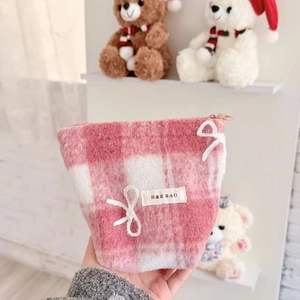 Pink checkered plush cosmetic bag with H&R logo in a cozy nursery room setting