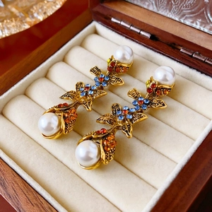 Détail macro de boucles d'oreilles florales dorées avec cristaux bleus et perles