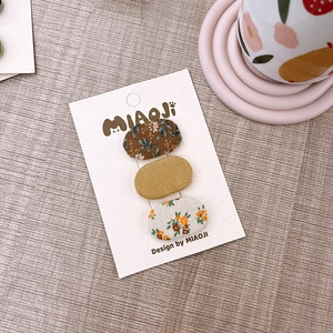 Dettaglio di tre fermagli per capelli ovali in tessuto floreale per bambini su carta