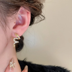 Elegant gold-plated dragon snake stud earrings with zircons shown on model ear